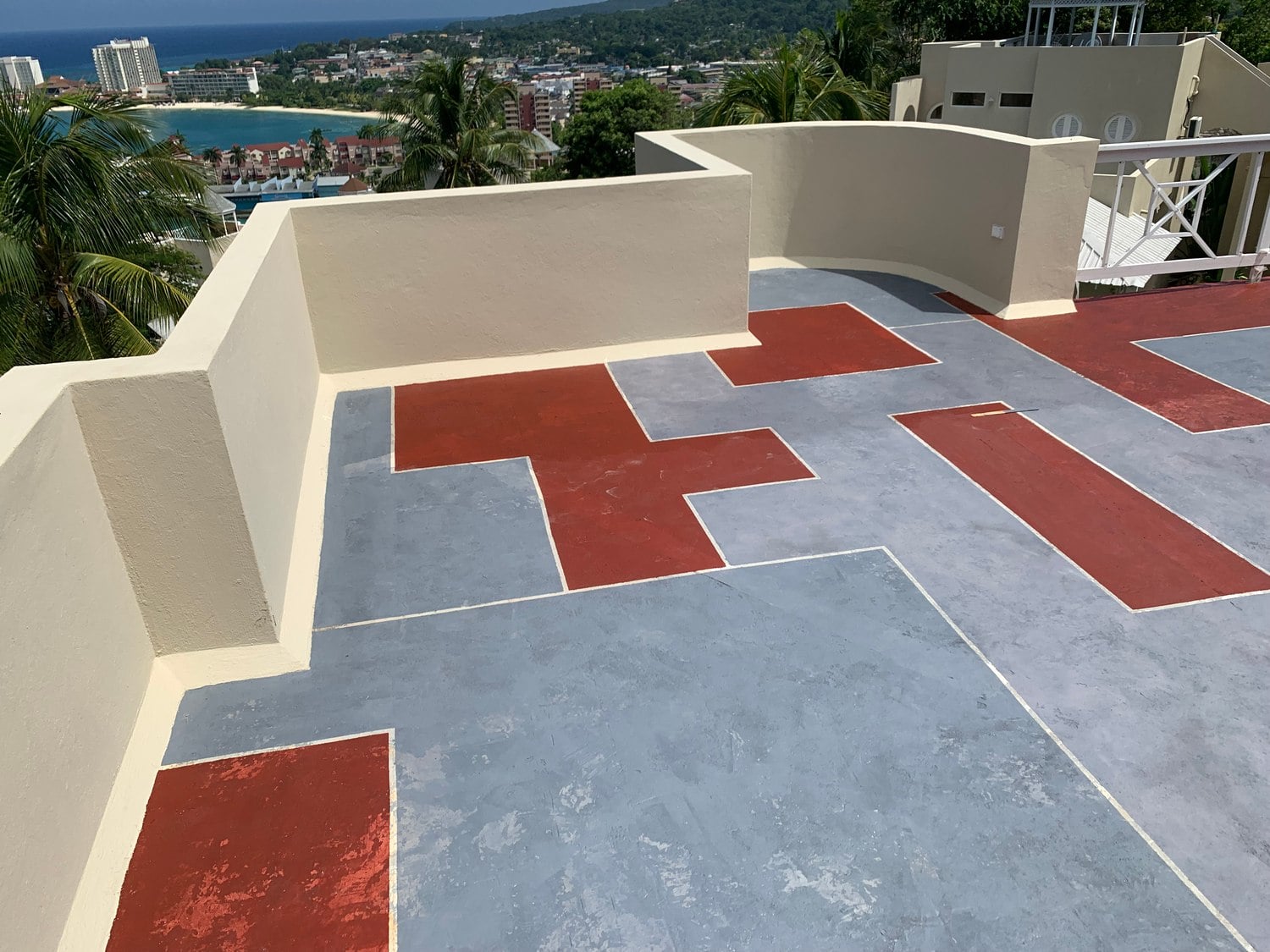 Red and grey geometric rooftop floor overlooking the Jamaican coast