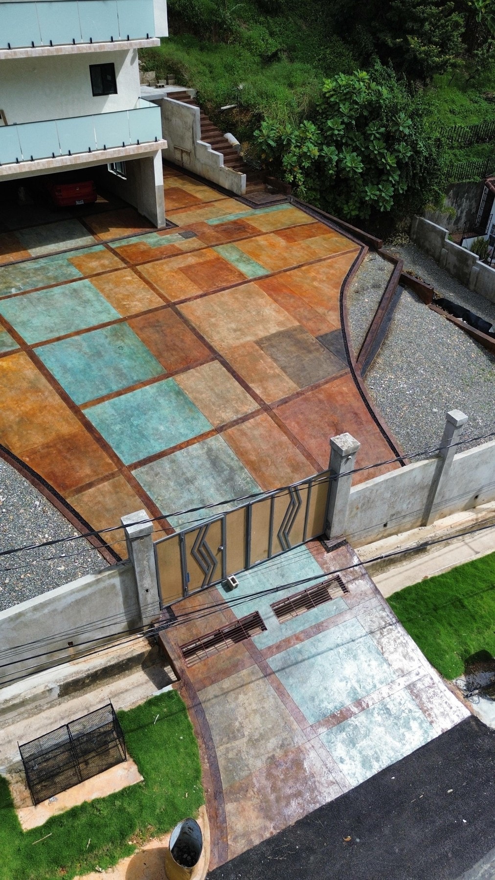 Turquoise, ochre and bronze geometric paving at the entrance to a modern house.