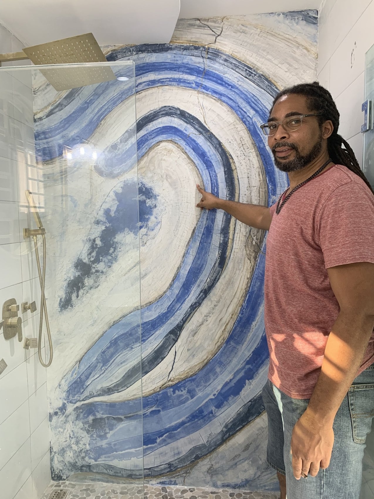 ExotiCrete founder Chalík Campbell beside the blue stone-effect Venetian plaster shower at an Airbnb in Columbus Heights, Ocho Rios