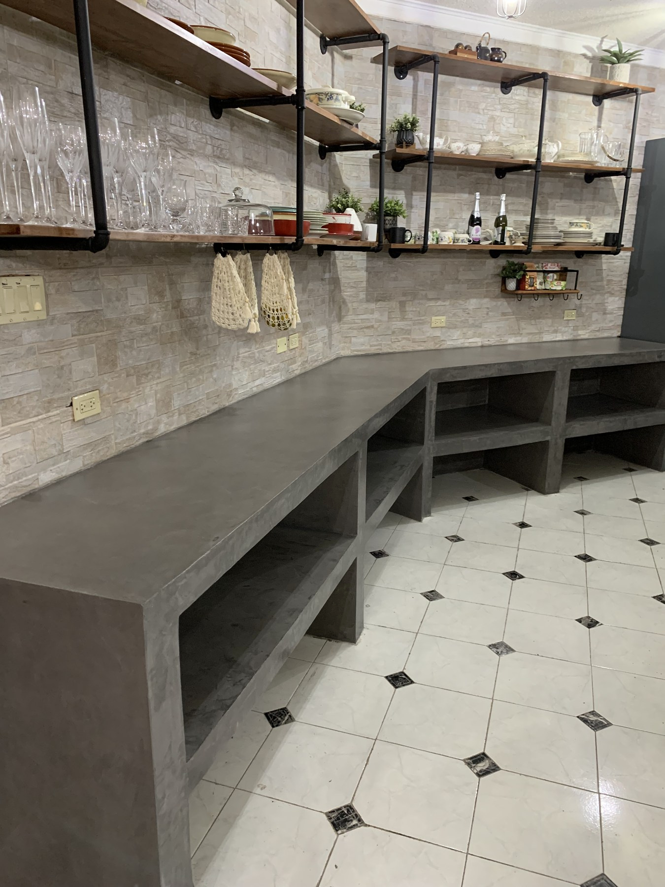 Concrete worktops and open cupboards follow the room, with a continuous hand-finished surface.