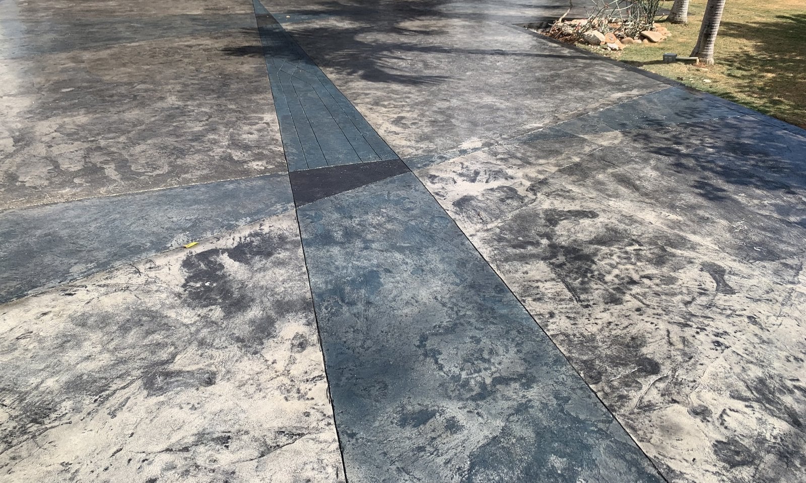 Slate-stamped texture meets dark geometric bands in the finished driveway surface.