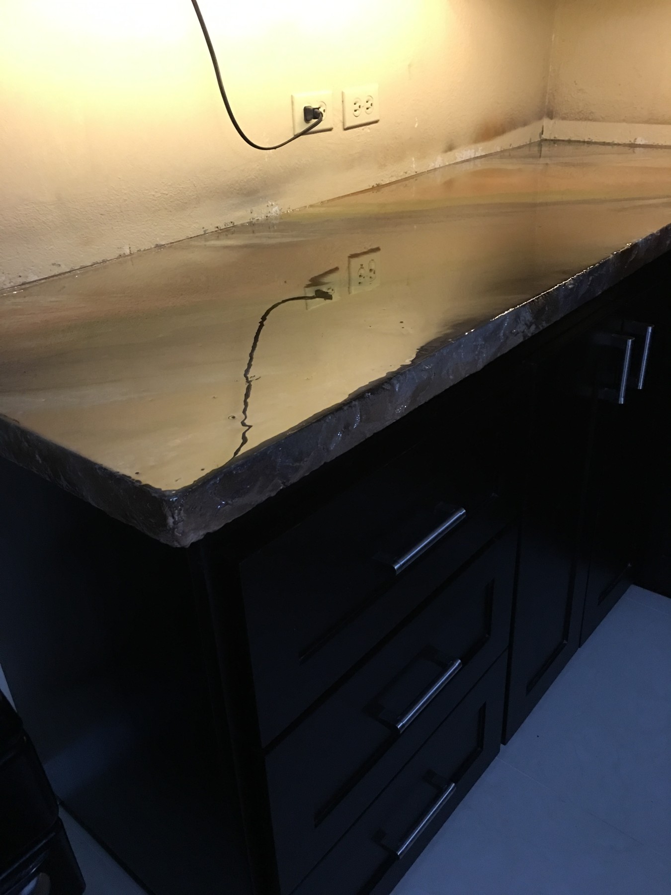 Warm metallic veining and the textured counter edge above the black cabinetry.