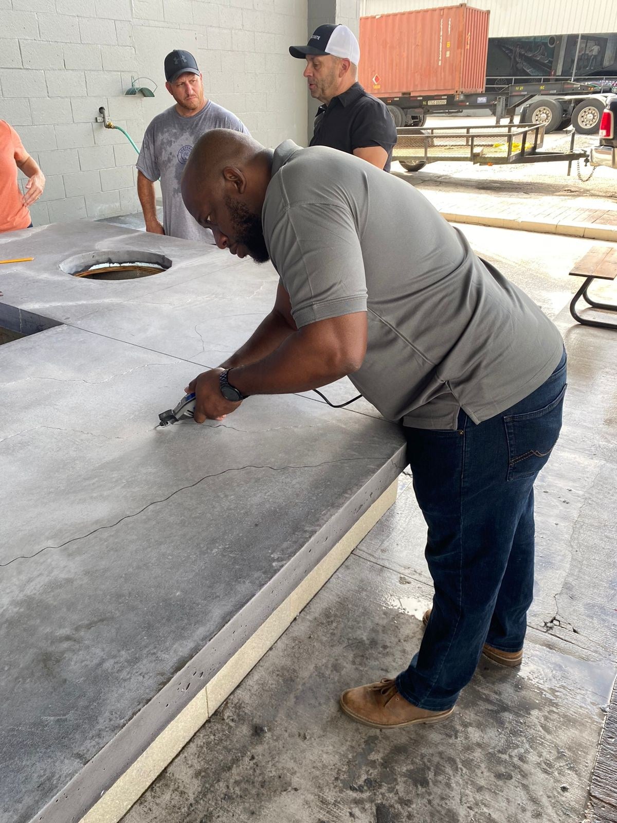 Carving stone-like lines into the grey countertop before staining at SureCrete training